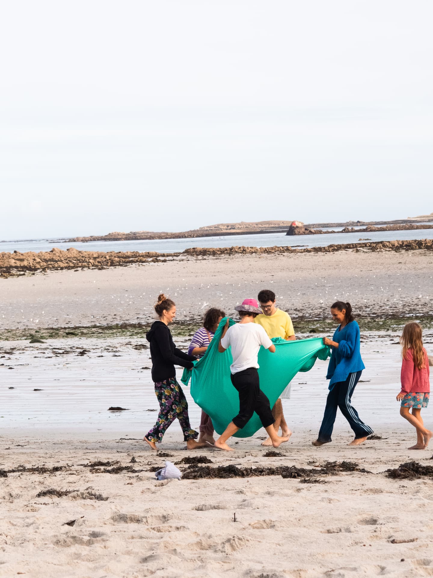 Participants tenant un grand tissu vert sur la plage